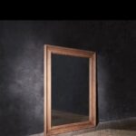 Imagen de inspiración de espejo de cuerpo entero con marco de madera natural envejecida apoyado en pared de estuco gris oscuro sobre suelo de parqué en espiga, estilo decorativo compatible con los espejos enmarcados a medida de Contell Marcs.