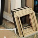 Varios marcos de madera natural en proceso de fabricación apilados en el suelo del taller Contell Marcs de Barcelona, mostrando el trabajo artesanal previo al acabado final.