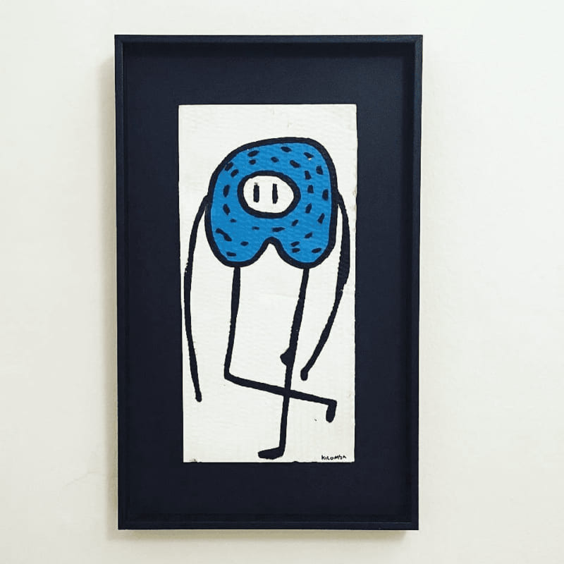 Marco negro con vitrina e ilustración de personaje azul con manchas y patas finas sobre papel blanco irregular, que crea efecto de profundidad, obra firmada por Kilomba, trabajo realizado por Contell Marcs.