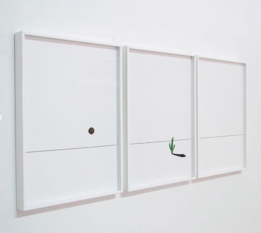 Tríptico de tres obras de arte contemporáneo minimalista con trazos en tinta negra sobre fondo blanco, enmarcadas con marcos blancos finos alineados en serie sobre pared blanca, instalación realizada por Contell Marcs.