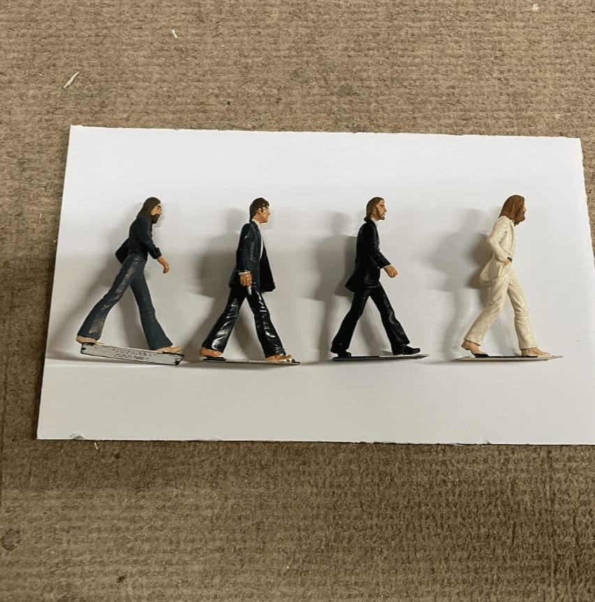 Cuatro figuras de músicos en miniatura pintadas a mano alineadas en fila sobre papel blanco, preparadas para ser montadas en vitrina diorama personalizada en el taller de Contell Marcs.