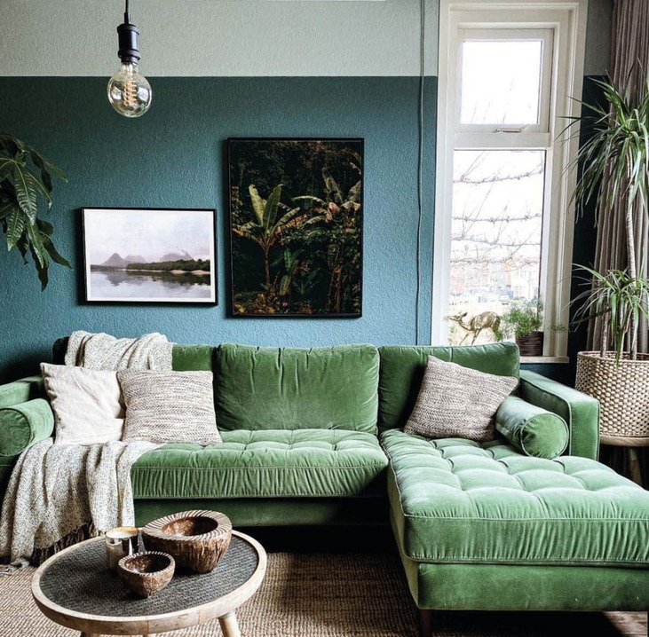 Imagen de inspiración de salón bohemio con pared verde oscura, sofá de terciopelo verde y dos cuadros con marcos negros finos colgados en composición asimétrica, estilo decorativo compatible con los marcos a medida de Contell Marcs Barcelona.