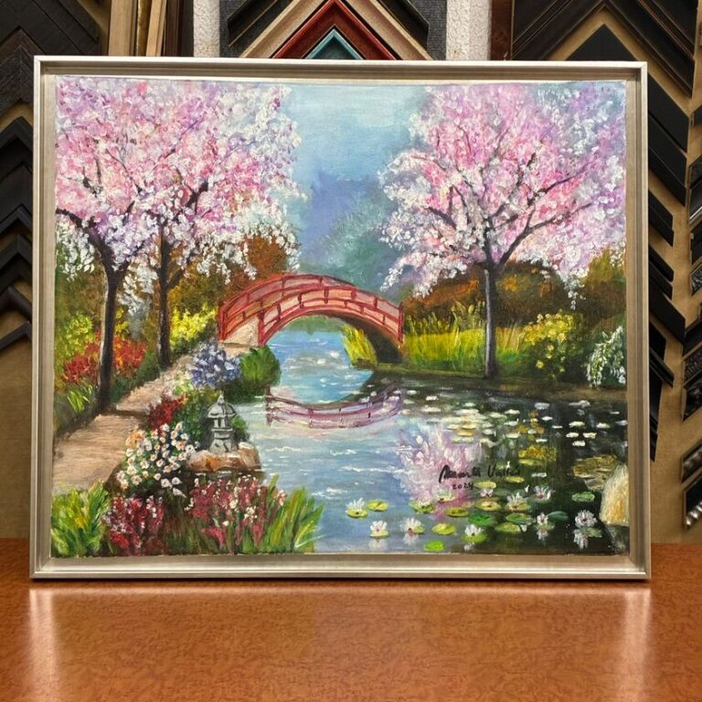 Pintura al óleo de jardín japonés con puente rojo, cerezos en flor rosa y estanque, enmarcada con marco de madera plateado de moldura tallada fina, trabajo de enmarcación realizado por Contell Marcs Barcelona.