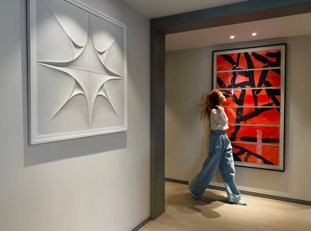 Cuadros salón modernos, se muestra un pasillo con dos cuadros : uno con una forma geométrica, y otro cuadro colorido rojo y negro.